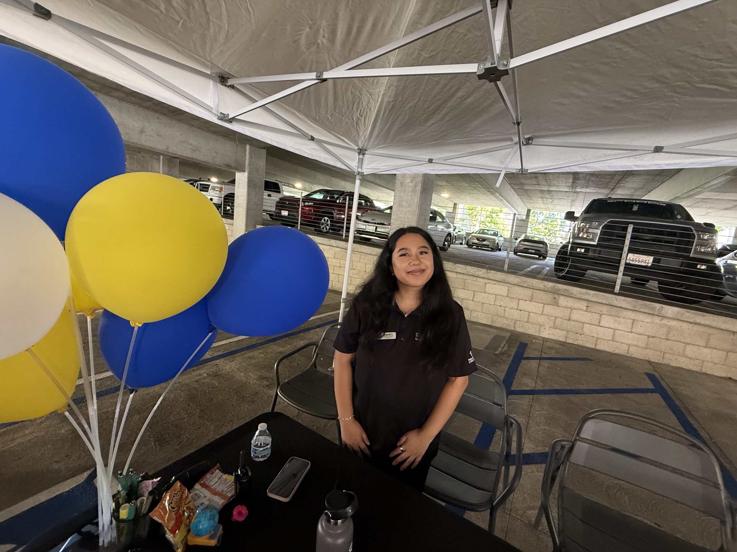 Person at a UCI move-in welcome table beside blue and yellow balloons