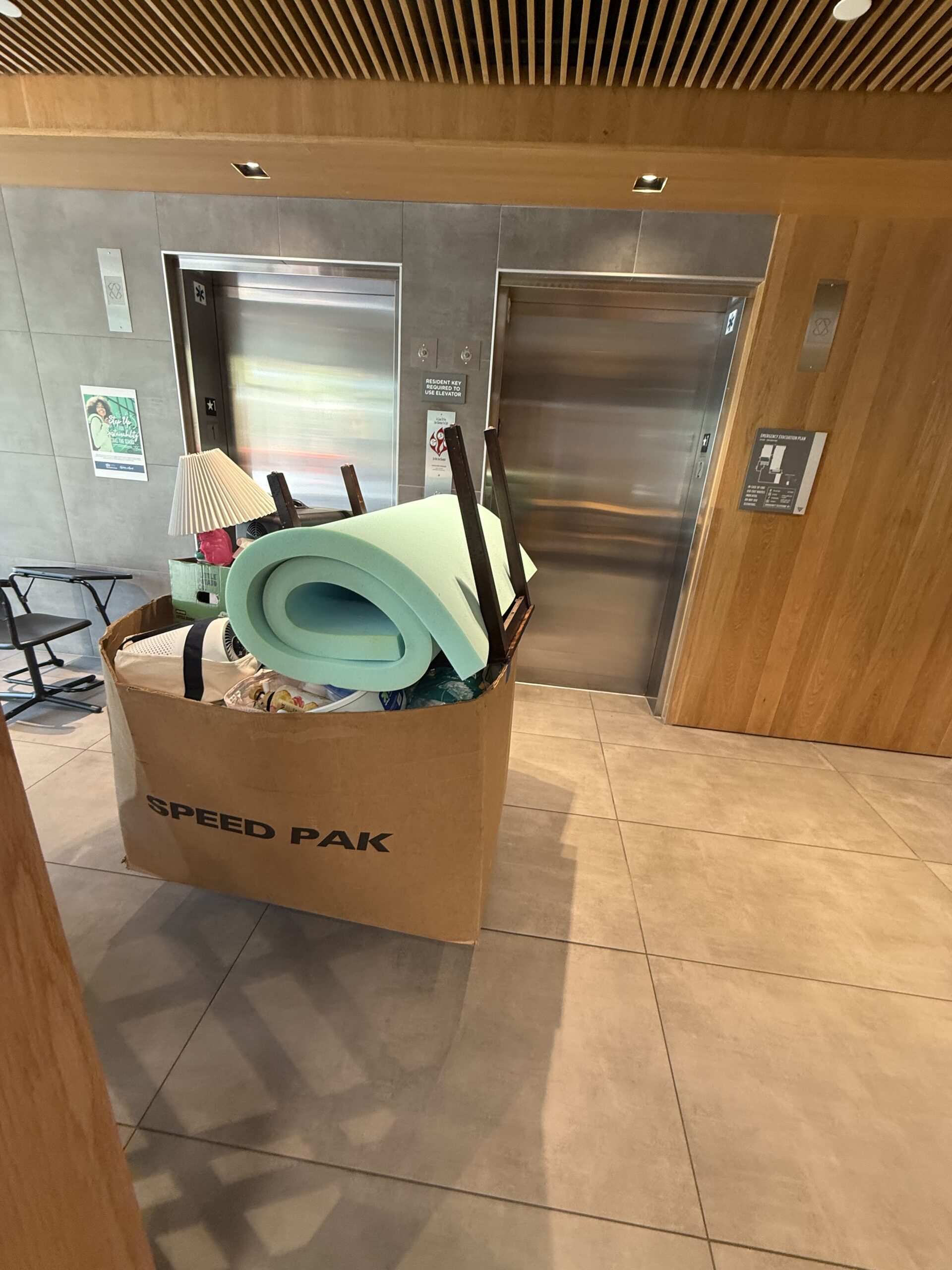 Loaded moving bin with belongings beside Plaza Verde elevators